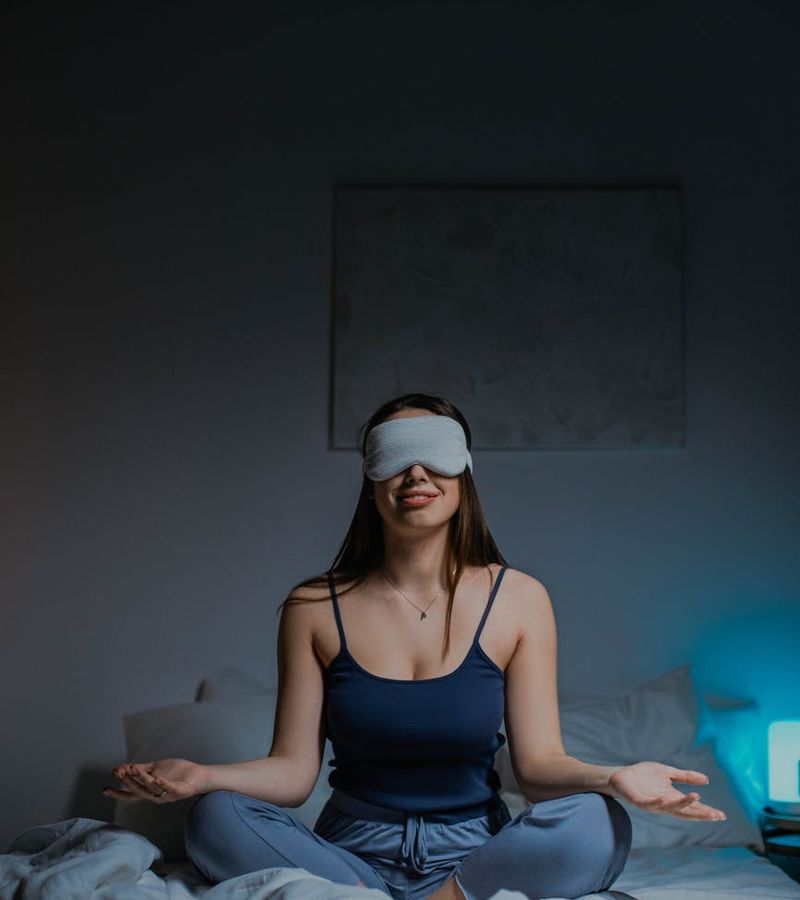 A person sitting cross-legged, meditating in a calm environment with a cobalt blue aura.