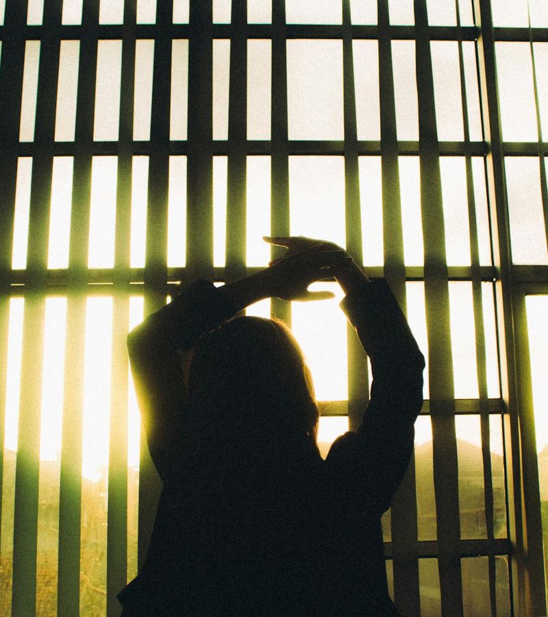 Woman in a peaceful morning yoga pose, backlit by a soft blue light.